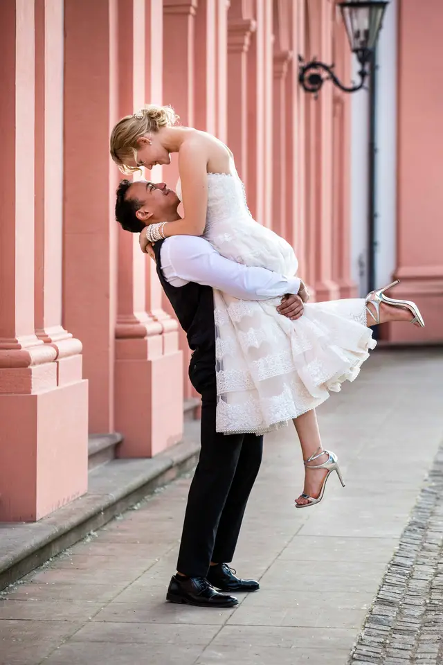 Laurin hebt Sanja vor den rosa Säulen von Schloss Biebrich
